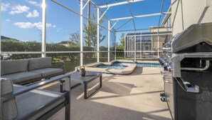 Eine Außenpatio mit Grill, Whirlpool und Sitzgelegenheit.