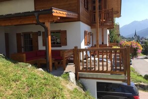 A wooden building with a balcony, a red bench, and a car parked in front. - Beautiful Alpine Chalet With Sauna (Wald im Pinzgau)