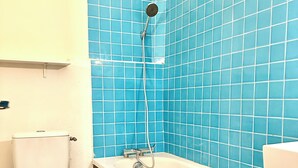 A bathroom with a white toilet, a bathtub, and a shower with a handheld showerhead. - Comfortable apartment Paris 75009 (Paris)