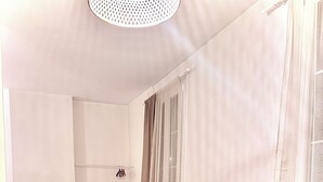 A small, well-lit room with a bed, a sofa, a TV, and a window with curtains. - Comfortable apartment Paris 75009 (Paris)