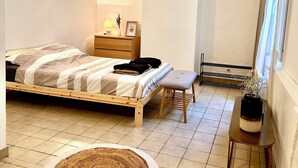 A bedroom with a bed, bedside table, lamp, and a small stool. - Comfortable apartment Paris 75009 (Paris)