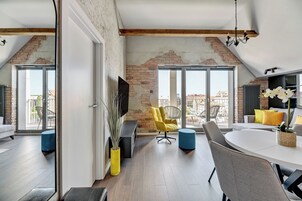 Una sala de estar moderna con pared de ladrillo, un ventanal grande y un comedor con una mesa redonda y sillas.