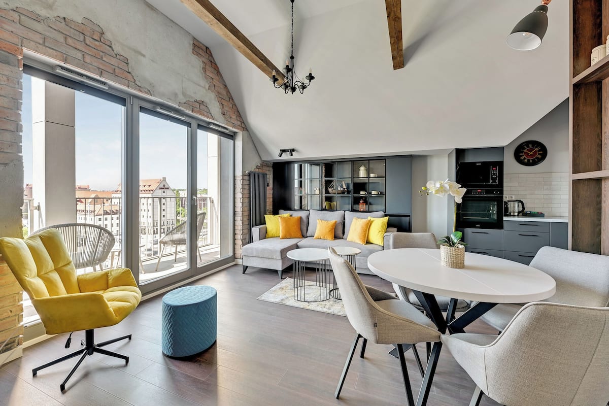 Un salon moderne avec un canapé, un fauteuil jaune et une table à manger ronde.