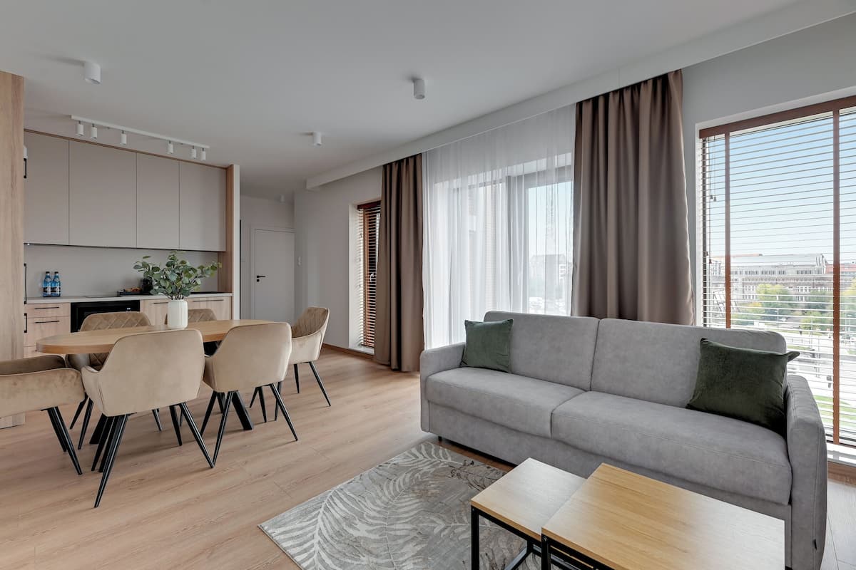 Un salon moderne avec un canapé gris, une table basse en bois et un coin repas comprenant une table et des chaises.