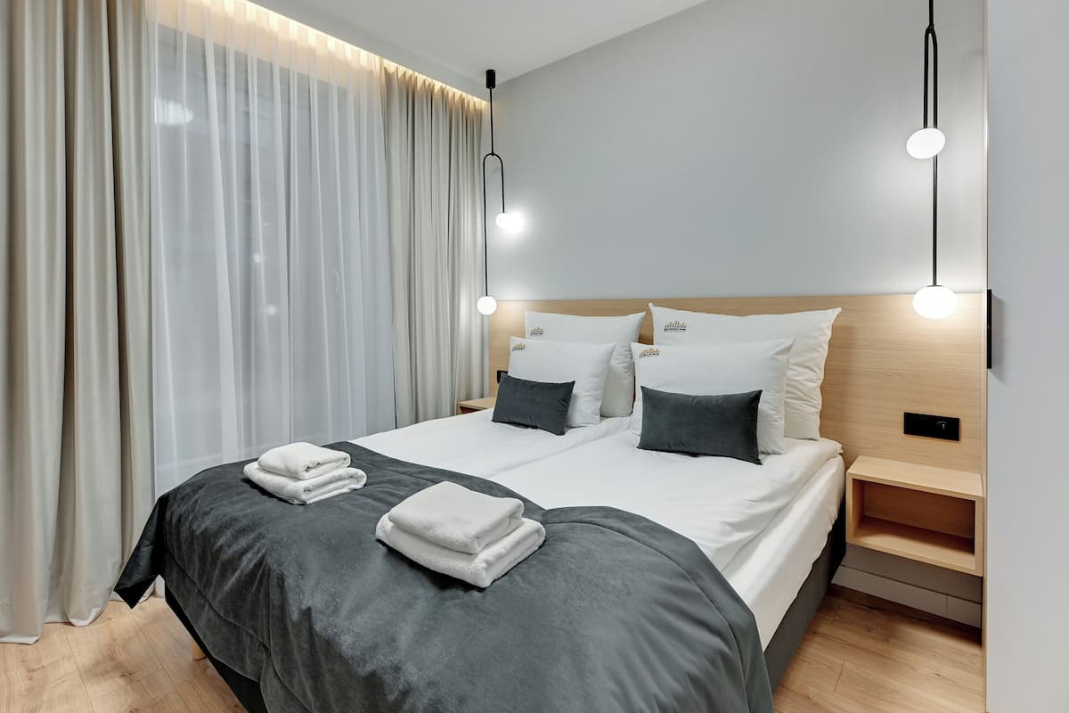 Une chambre d’hôtel moderne avec un lit bien fait, une table de chevet et un luminaire suspendu.