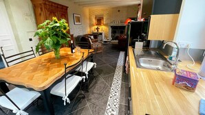 A compact kitchen with a wooden dining table, chairs, a sink, and a small refrigerator. - Charming cottage in Touraine with garden, near Loire castles (Avon-les-Roches)