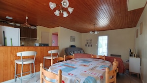 A cozy kitchen with wooden cabinets, a dining area with a table set for four, and a ceiling fan. - Quiet Vacation Home - Pets Allowed (La Faute-sur-Mer)