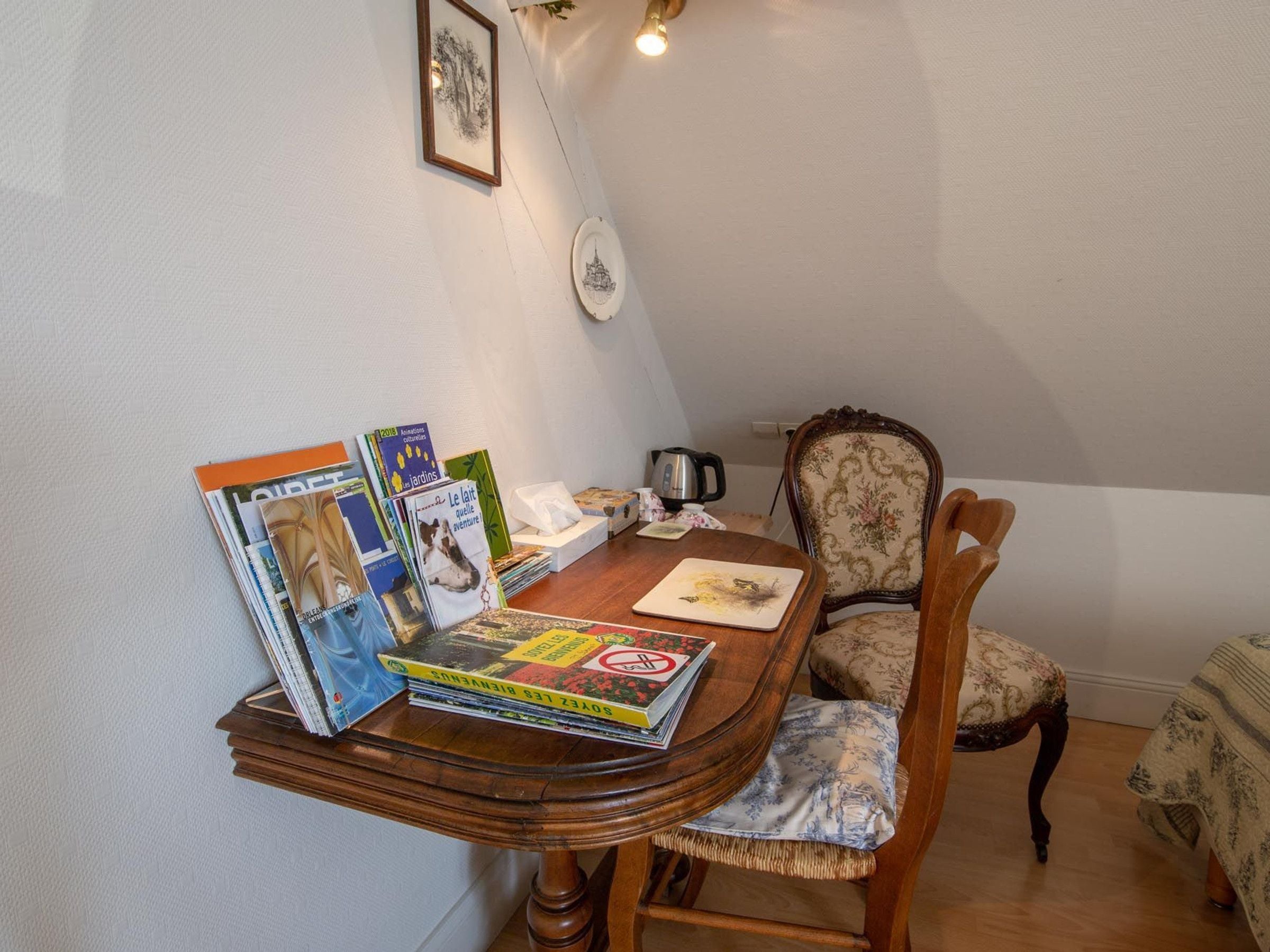 Un petit coin repas avec une table en bois, une chaise et une pile de livres.