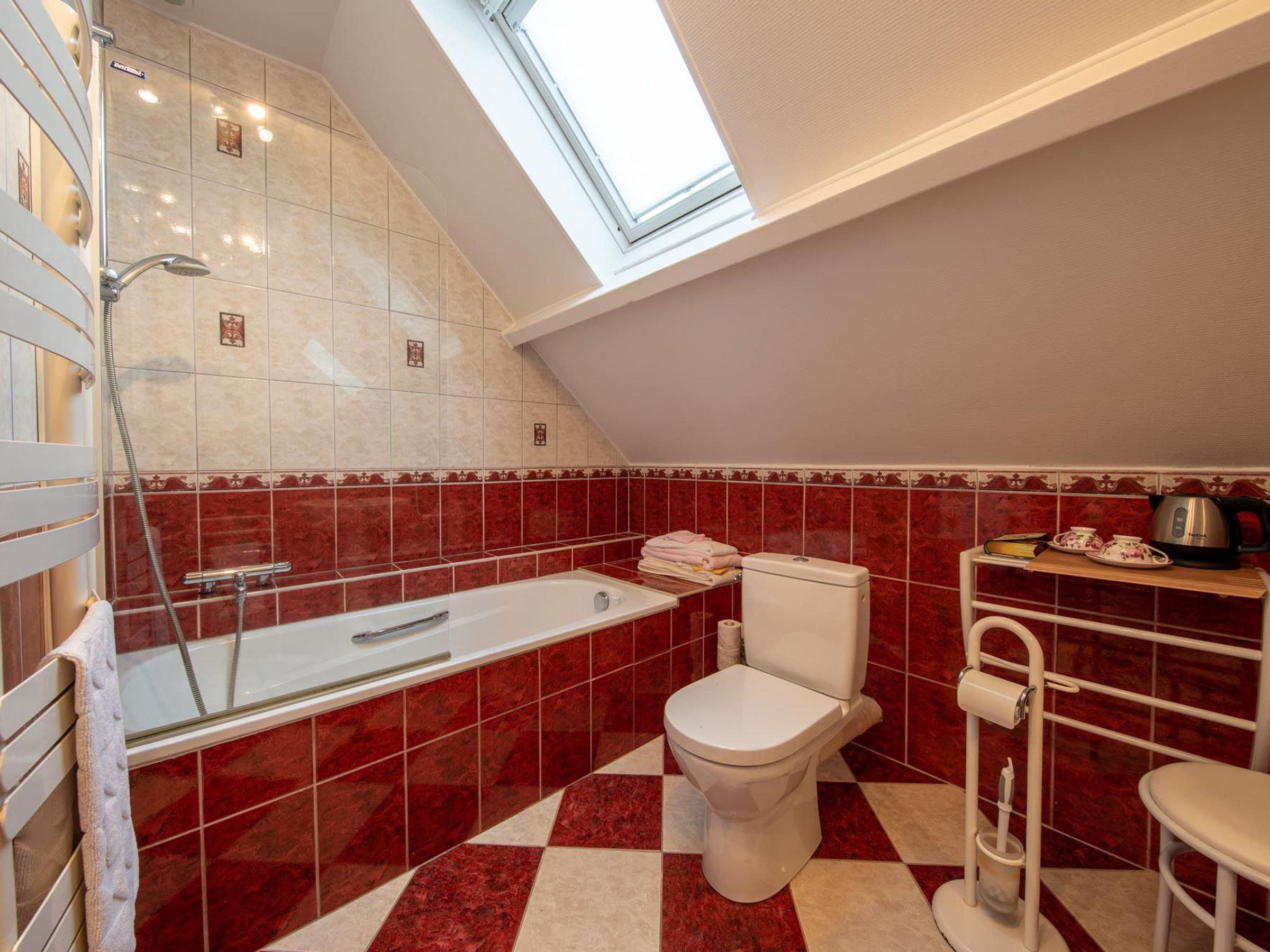 Un baño con tragaluz, bañera, inodoro y lavabo.
