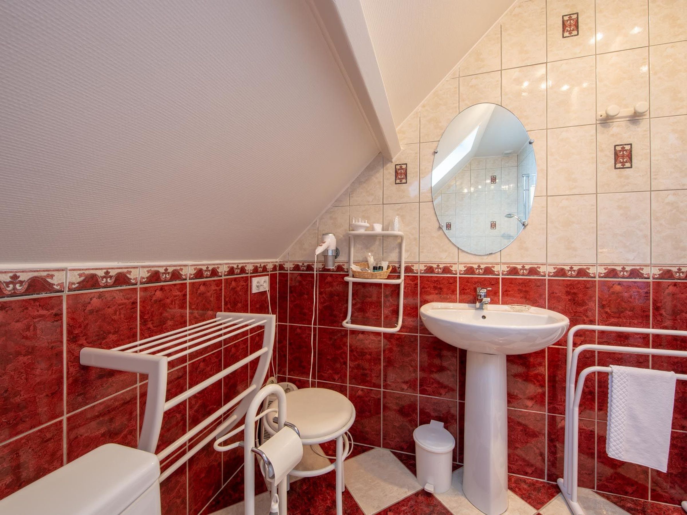 Un bagno con il water bianco, un lavabo, uno specchio e una parete rivestita di piastrelle rosse.