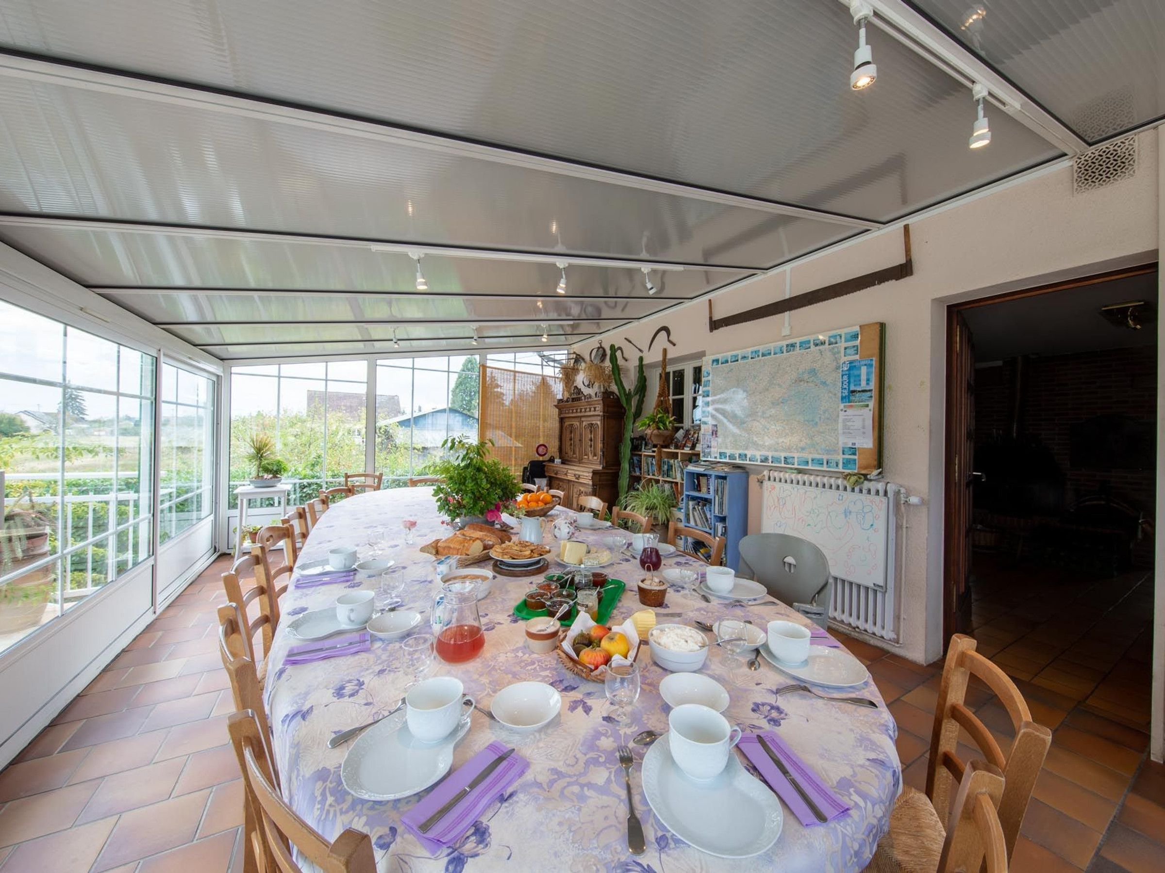 Un coin repas avec une table ronde dressée pour un repas, entourée de chaises, et offrant une vue sur la verdure à l’extérieur.