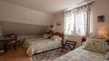 Une chambre avec deux lits, une chaise en bois, une petite table et une fenêtre avec des rideaux.