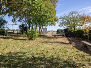 A backyard with a swing set, a small shed, and a stone bench. - Comfortable family suite with WiFi in Saint-Benoît-sur-Loire, pets allowed (Saint-Benoît-sur-Loire)