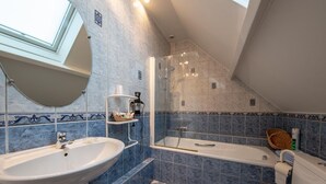 Une salle de bain avec un puits de lumière, une baignoire, des toilettes et un lavabo.