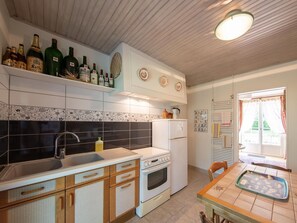 A kitchen with a sink, stove, refrigerator, and a dining area with a table. - Room La Loire - Disabled Access, WiFi, Pets Allowed (Saint-Benoît-sur-Loire)