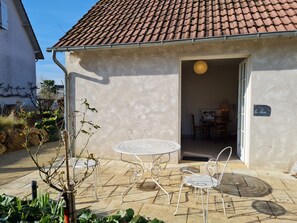 A patio with a round table and two chairs, a door leading to an interior space, and a sign on the wall.