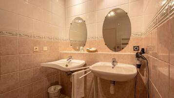 Une salle de bain avec deux lavabos, un miroir et une poubelle.