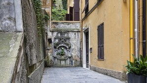 A narrow alleyway with a stone wall on one side and a yellow building on the other. - Elaisa s House - RS (Genoa)