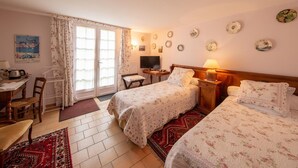 A hotel room with two beds, a desk, a chair, a television, and a dining area. - Charming room with private terrace and wifi in Saint-Benoît-sur-Loire (Saint-Benoît-sur-Loire)