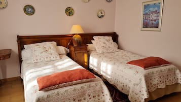 Un lit double avec une literie à motifs floraux et une table de chevet avec une lampe.