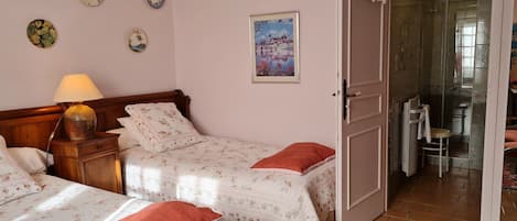 Ein Schlafzimmer mit zwei Betten, einem Nachttisch, einer Lampe und einer Tür zu einem Badezimmer.