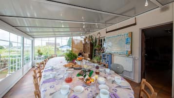 Un comedor con una mesa redonda dispuesta para una comida, rodeada de sillas, y vista a zonas verdes.