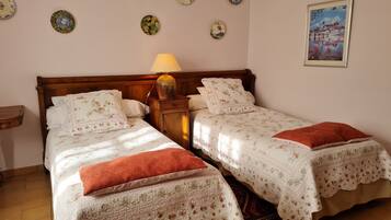 Un lit double avec une literie à motifs floraux et une table de chevet avec une lampe.