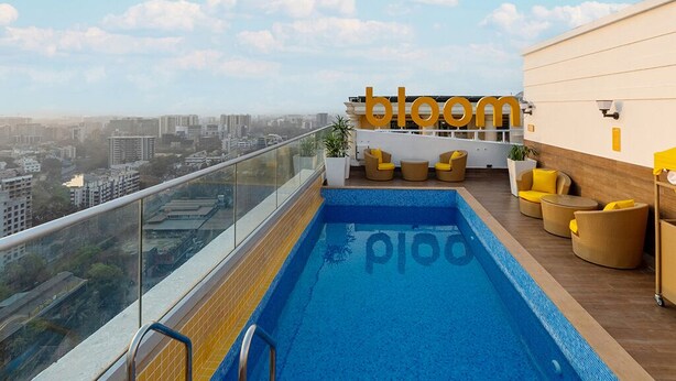 A rooftop pool with a city view, a 'bloom' sign, and yellow and brown seating. - Bloom Hotel Saki Vihar (Mumbai)