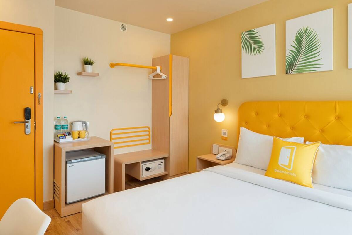 A hotel room with a bed, a desk, a mini-fridge, a wardrobe, and a bathroom.