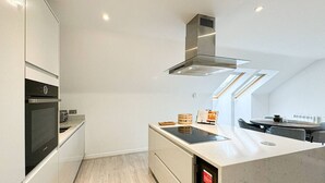 Een moderne keuken met inbouwapparatuur, een centraal eiland en een eethoek met een tafel en stoelen.