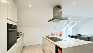 A modern kitchen with built-in appliances, a central island, and a dining area with a table and chairs.