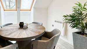 Een ronde eettafel met stoelen, een plant in pot en een radiator.