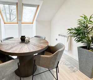 A round dining table with chairs, a potted plant, and a radiator.
