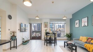 A modern living room with a dining area, a sofa, and a TV mounted on the wall. - New Listing | JBR Beach Gem | Czechin | 1BD (Dubai)