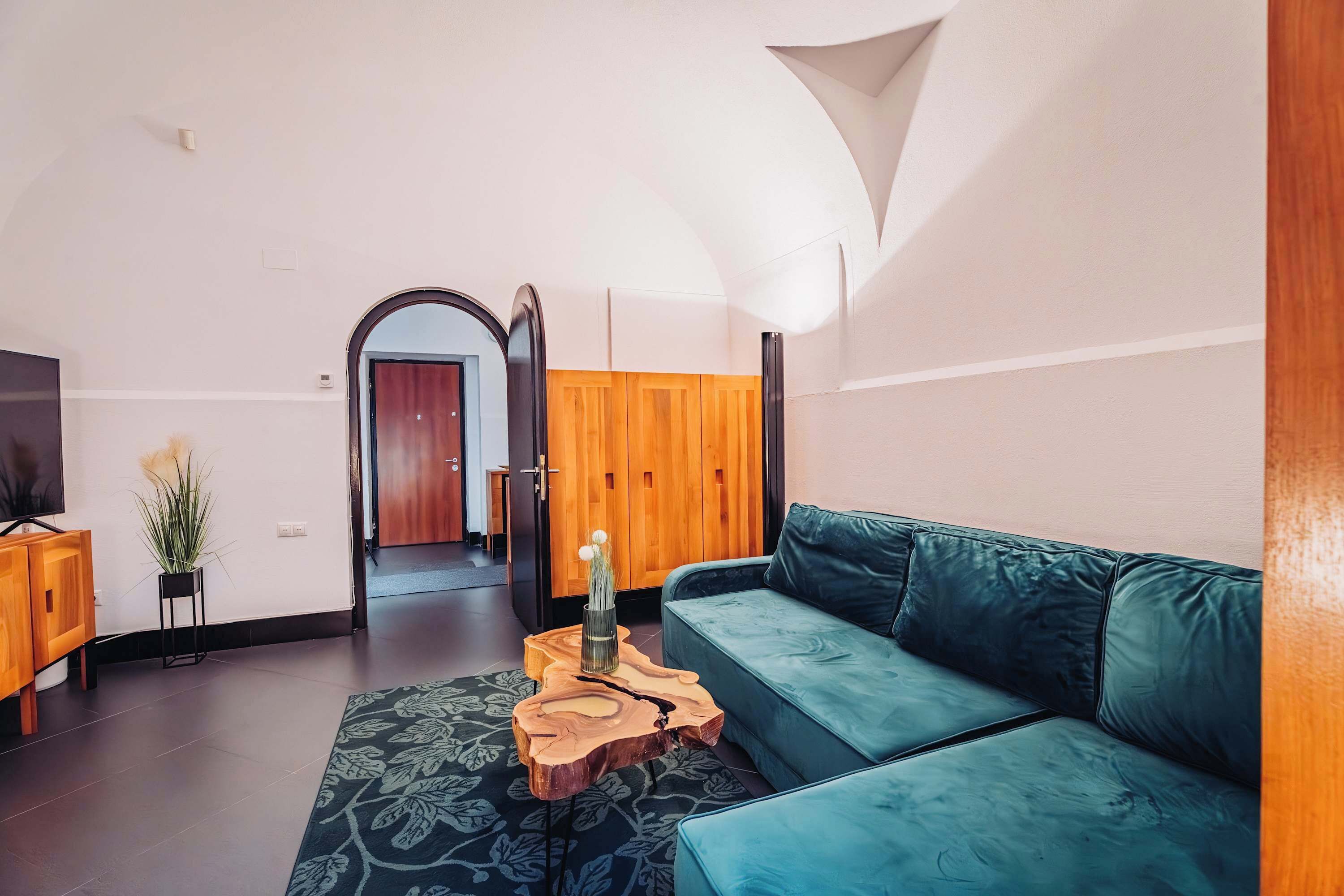 Uma sala de estar moderna com um sofá verde-água, uma mesa de centro de madeira e uma TV sobre um móvel de madeira.