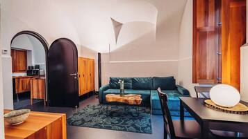 A compact living space with a kitchenette, a sofa, a dining table, and a unique ceiling design.