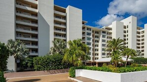 A modern hotel with multiple white buildings, balconies, and lush greenery. - Beachfront 2BR, 2BA condo with heated pool and beach access. (Marco Island)