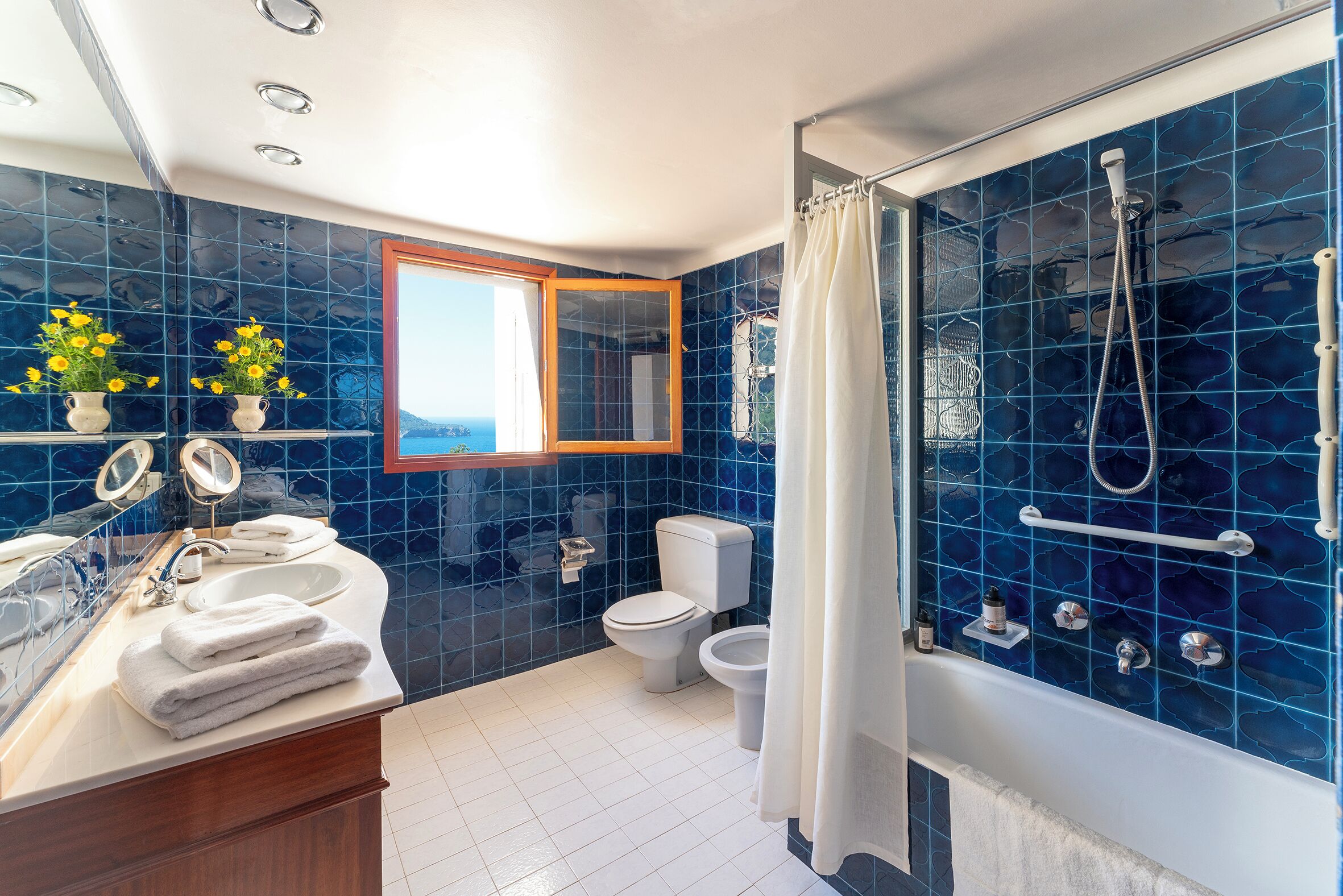 A modern bathroom with a large bathtub, a shower, and a toilet. There are two sinks and a mirror above the sink.