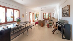 Amplia sala de estar con piano, comedor y ventanas grandes.