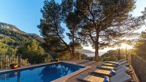 Zona de piscina con sillones de descanso y vistas a las montañas.