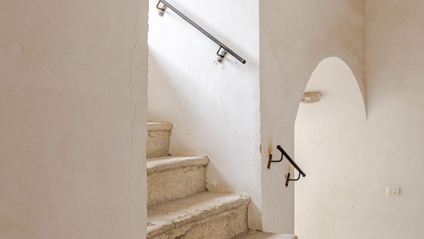 A staircase with stone steps and a metal handrail, leading to an arched doorway. - [salernostays] Central apt by duomo | Retro Vibes (Salerno)
