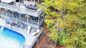 Una casa a due piani con un'ampia terrazza, una vasca idromassaggio e una piscina.