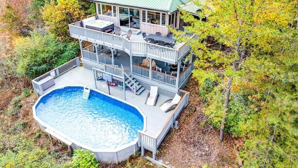 Una casa a due piani con un'ampia terrazza, una piscina e un tetto verde.
