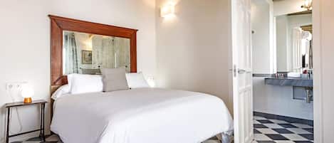A hotel room with a bed, bedside table, and a bathroom visible through an open door.