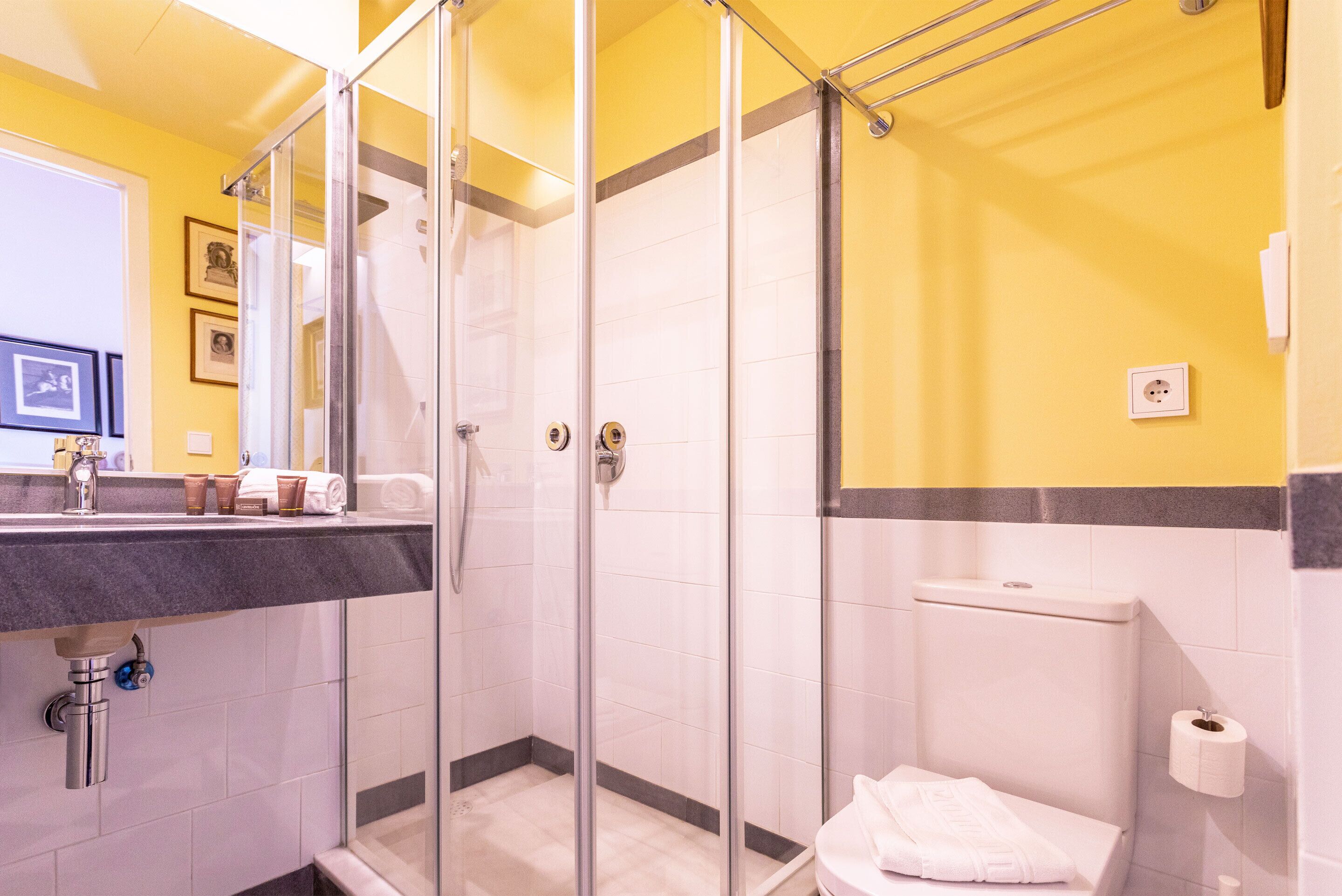 Un baño con cabina de ducha de vidrio, lavabo con espejo e inodoro.
