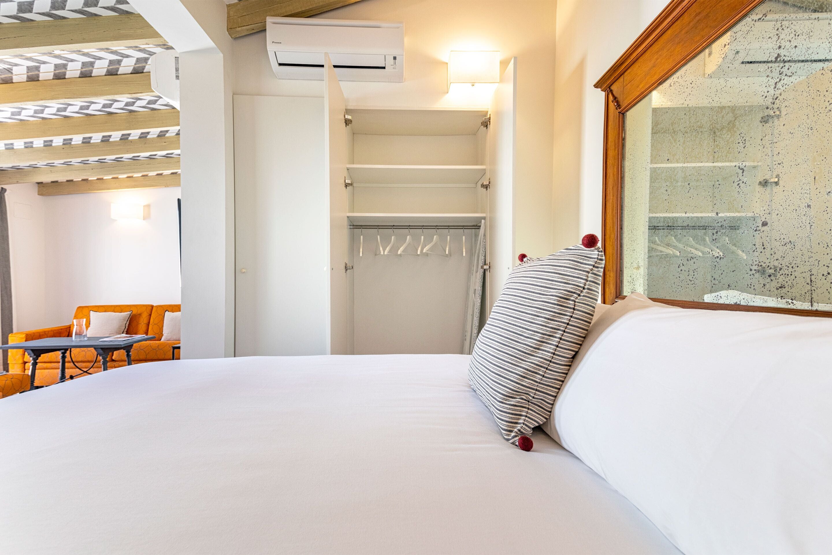 Habitación de hotel con cama, armario, una mesita con una silla y ventana con vistas.