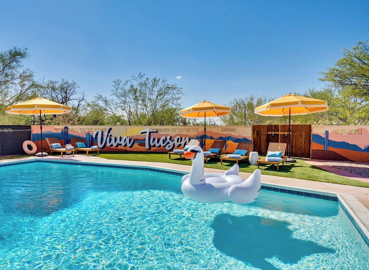 A swimming pool with a swan float, lounge chairs, and umbrellas.