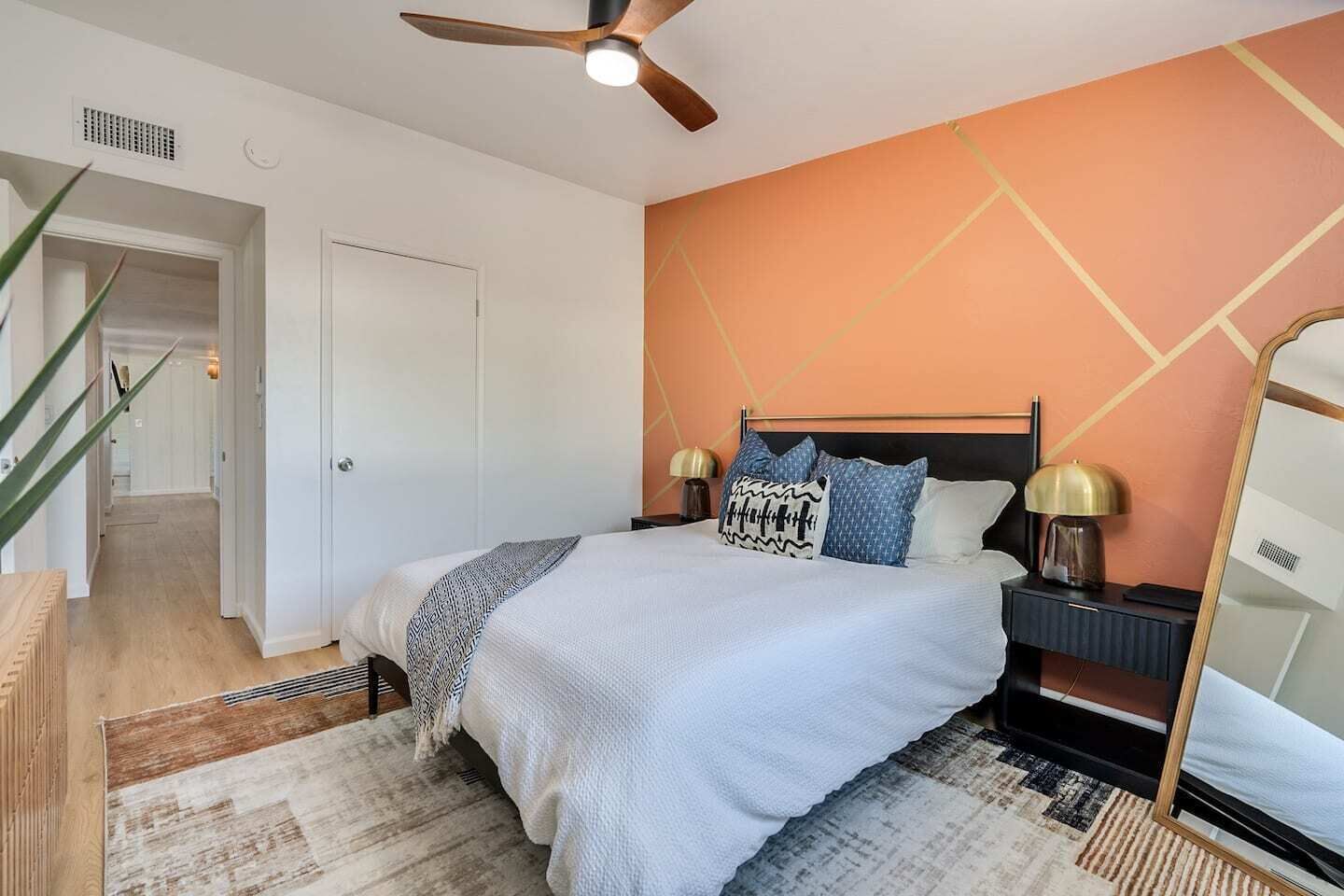 A bedroom with a bed, bedside tables, a ceiling fan, and a large mirror.