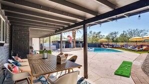 En overdækket terrasse med pool, udendørs møbler og udsigt over det omkringliggende landskab.