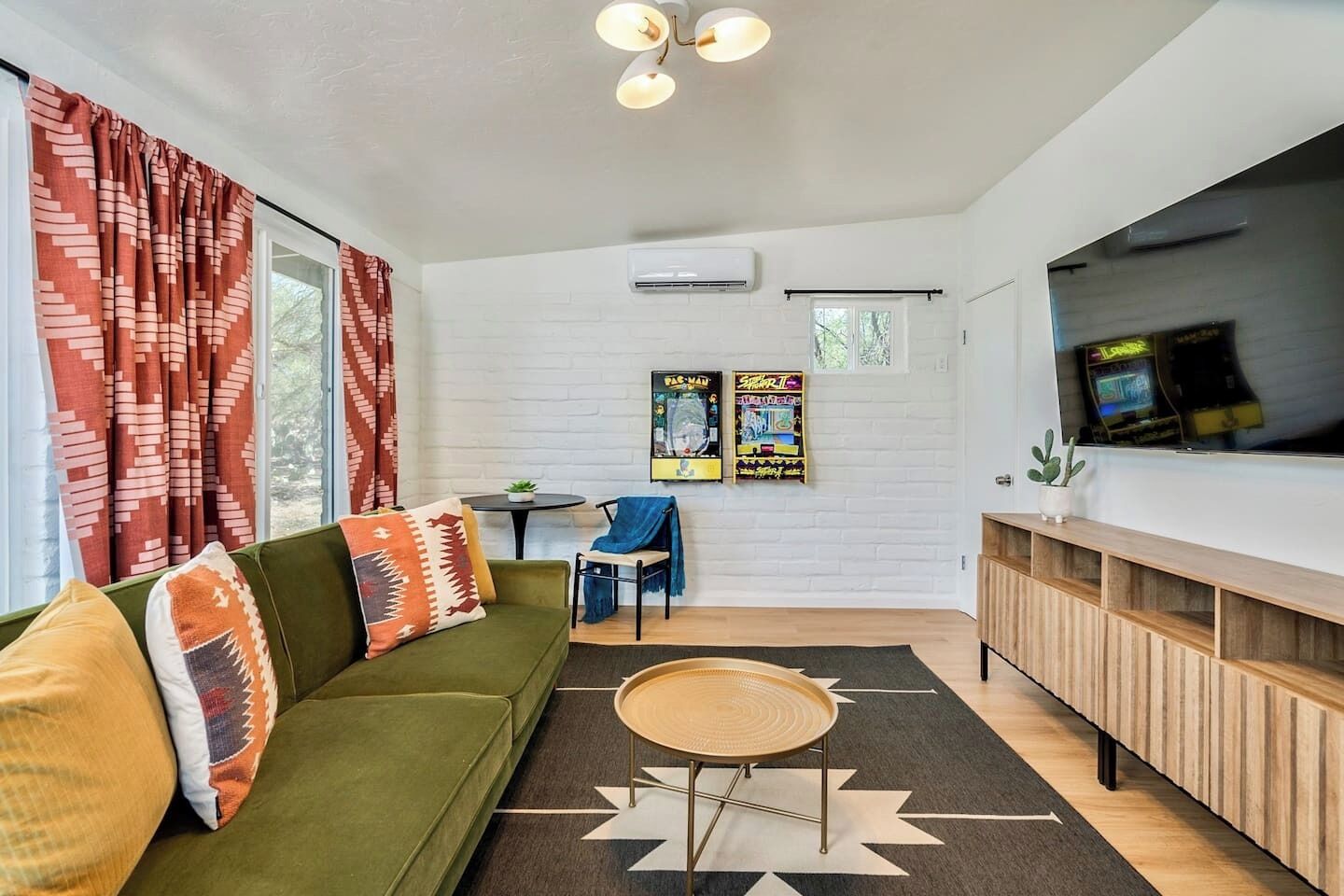 Un salon moderne avec un canapé vert, une petite table ronde et un téléviseur fixé au mur.